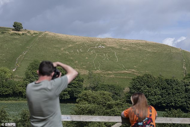 Workers manually restore historic Cerne Abbas Giant with 17 tonnes of chalk.